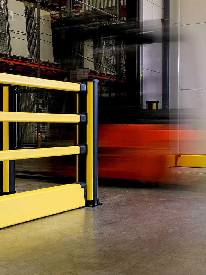 Heavy-duty yellow and black crash barrier installed in a warehouse to protect pedestrians and infrastructure from forklift collisions. Industrial safety barriers like this are essential for impact protection and accident prevention in high-traffic logistics and manufacturing environments.