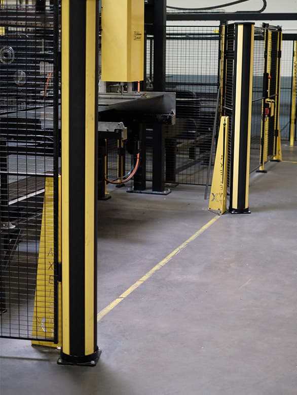 A light barrier system installed near industrial machinery, designed to stop machine movement when someone enters the detection zone. The image highlights the role of presence sensors in ensuring safe access to large machinery systems and preventing workplace accidents.