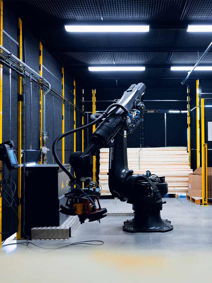 A robotic arm in an industrial setting, surrounded by protective black sheet metal panels. The image emphasizes the importance of machine safety in automated environments, ensuring secure operations and minimizing workplace hazards.