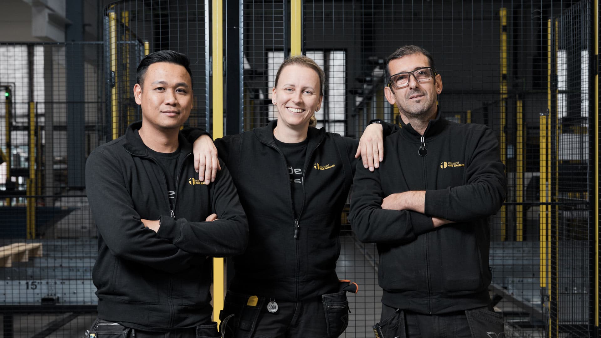Two men and on woman standing infront of machine guards