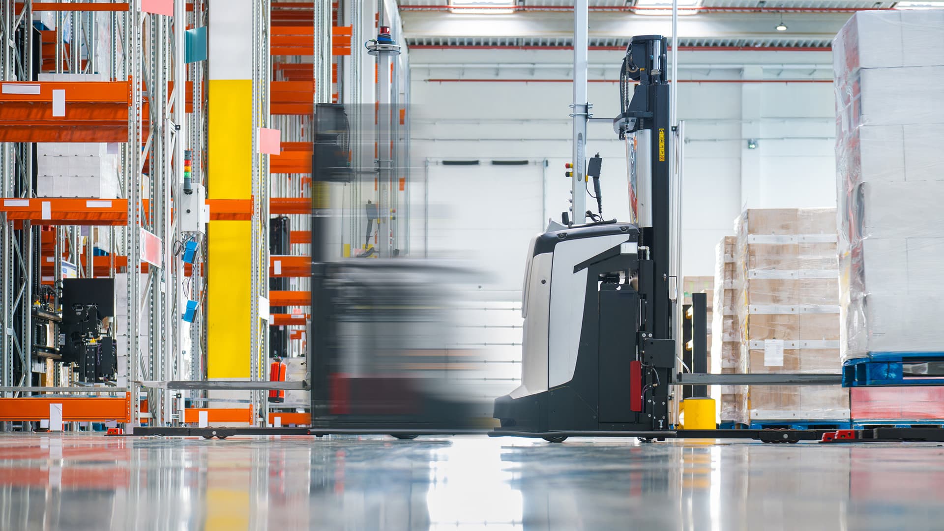 An AVG transports a pallet in a warehouse for automated material handling
