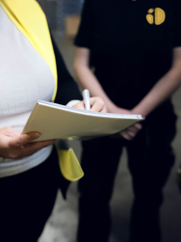 Close-up of an industrial safety professional taking notes during a compliance inspection. The image highlights the importance of workplace safety audits, global machinery regulations, and adherence to industrial safety standards to ensure a secure work environment.