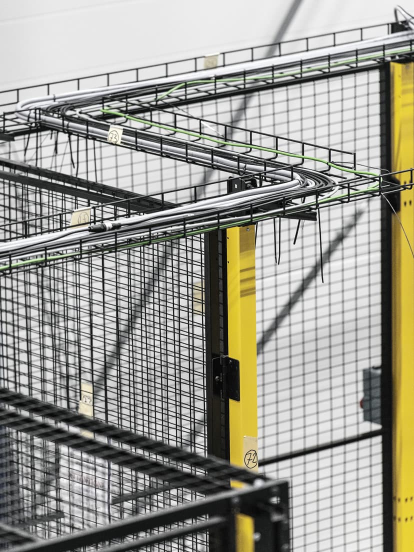 Industrial guard fencing with neatly arranged electrical cables routed along the top. The image highlights the importance of protective bonding in preventing electrical hazards and ensuring safe, grounded installations in industrial environments.