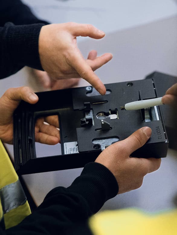 Close-up of two people examining a mechanical component, with one person pointing at a detail using a pen. The image highlights the importance of precision, collaboration, and thorough inspection in implementing effective machine safety measures in industrial environments.