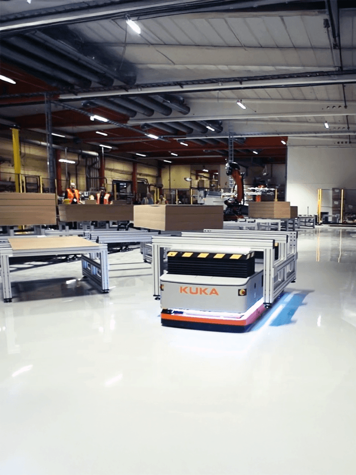 Industrial mobile robots operating in a warehouse with safety barriers separating pedestrian areas from robot paths