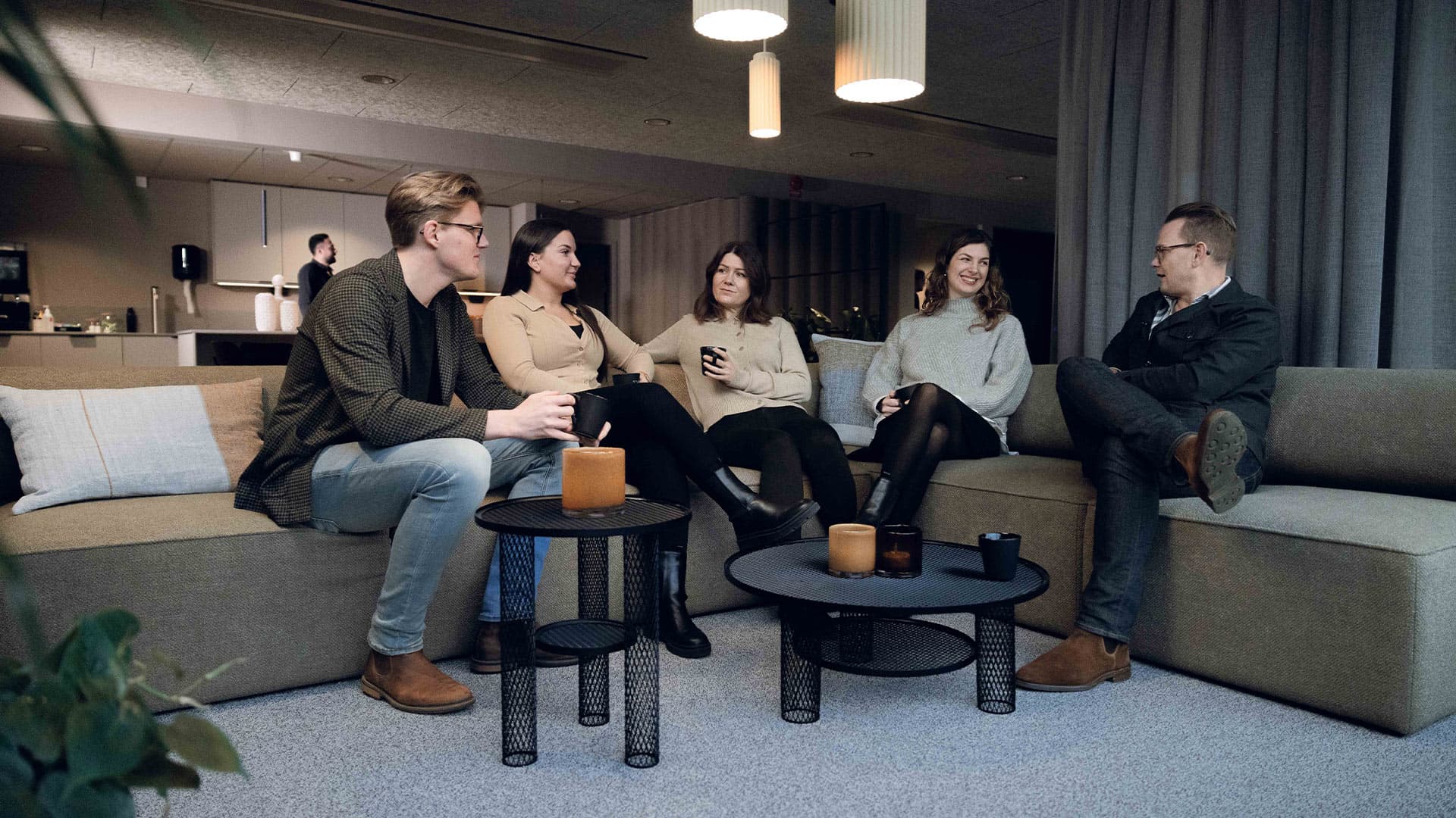 Two men and two women sitting in a sofa in the lounge at the office in Hillerstorp