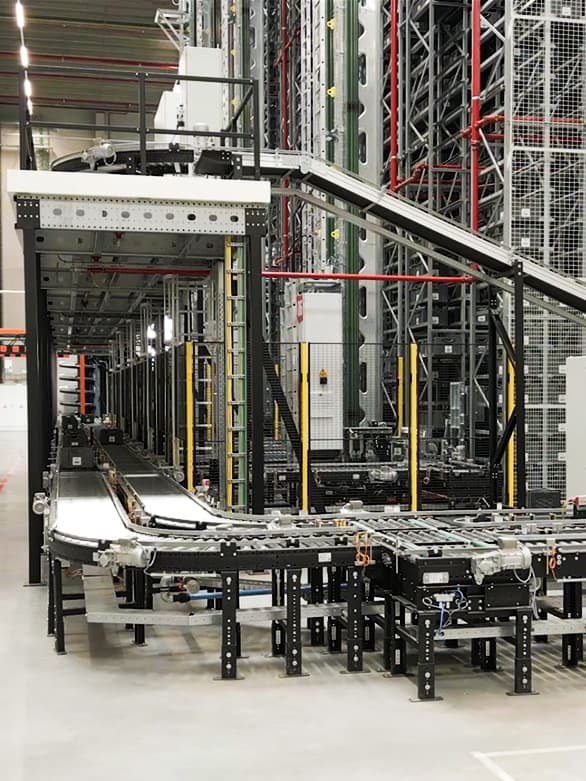 Automated roller and belt conveyor system in a warehouse, used for transporting totes and bins