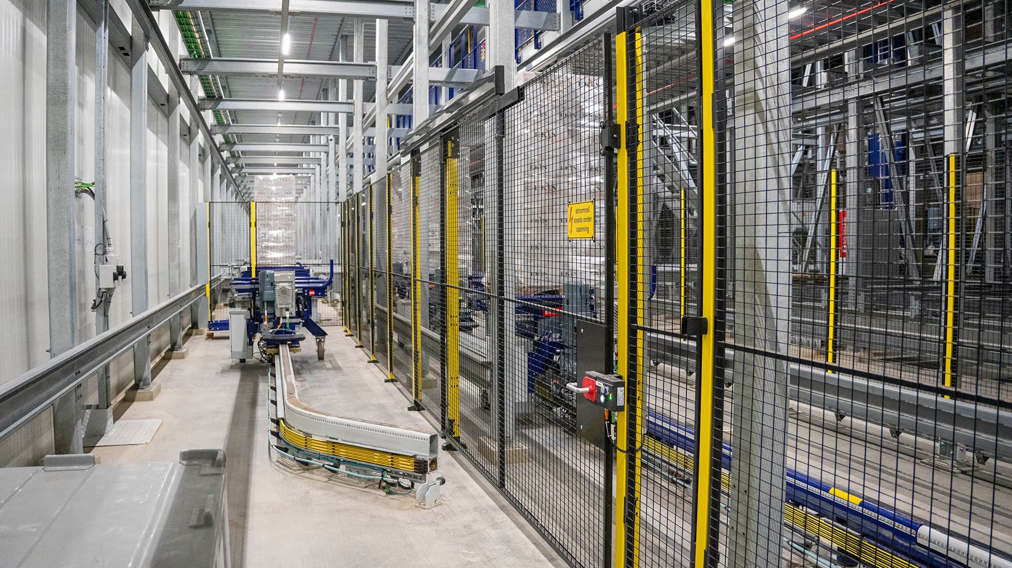 Industrial conveyor system operating within a fenced safety enclosure in a modern warehouse facility