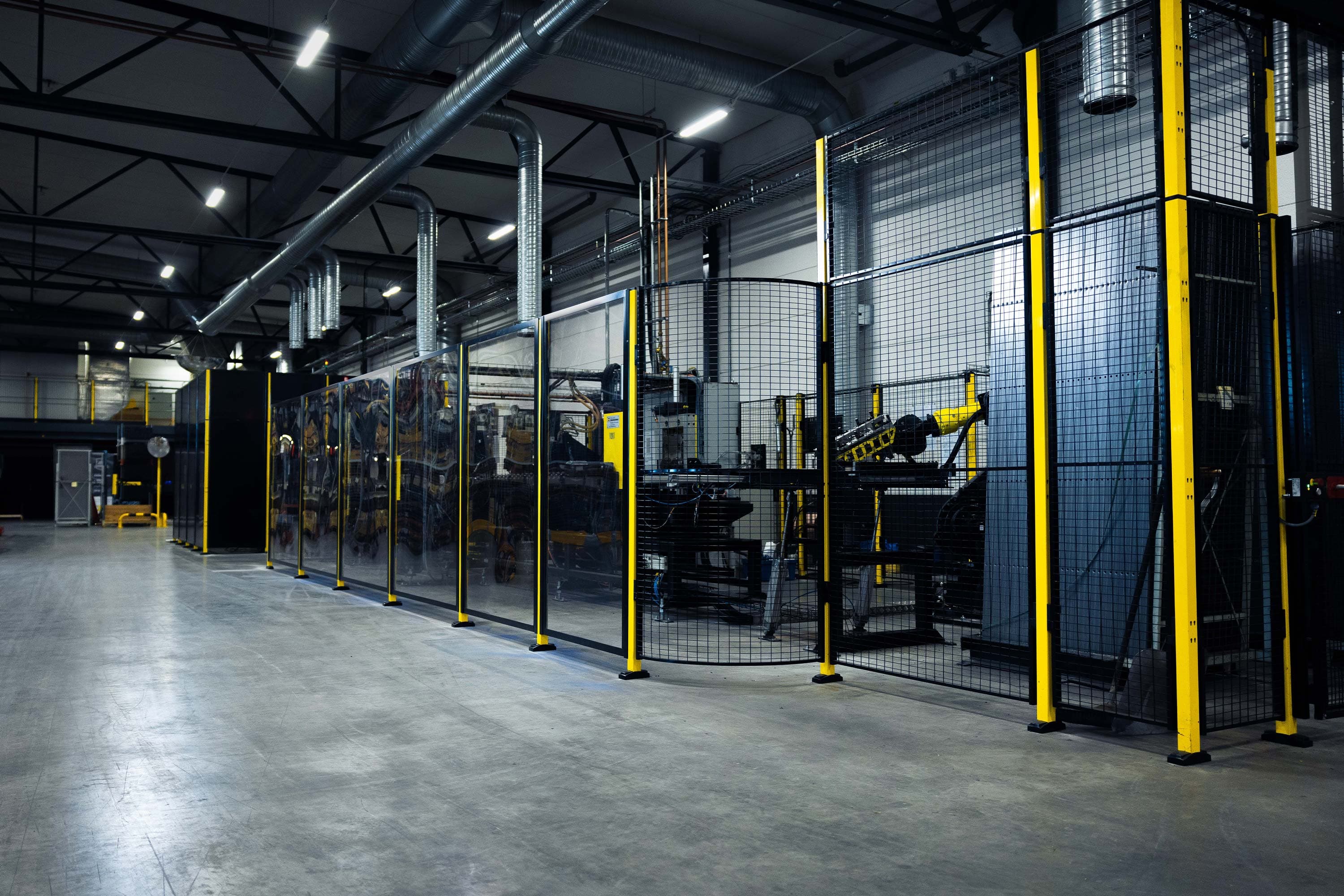Machine guarding and safety fencing protecting automated production equipment in an industrial facility