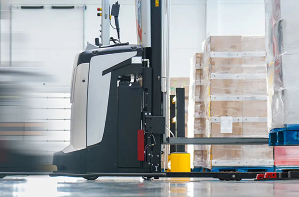 An AVG transports a pallet in a warehouse for automated material handling