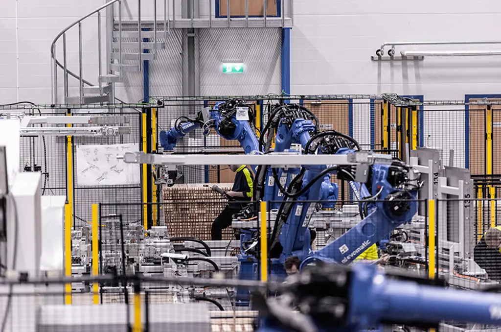 Robotic arms palletizing cartons inside safeguarded automation cell