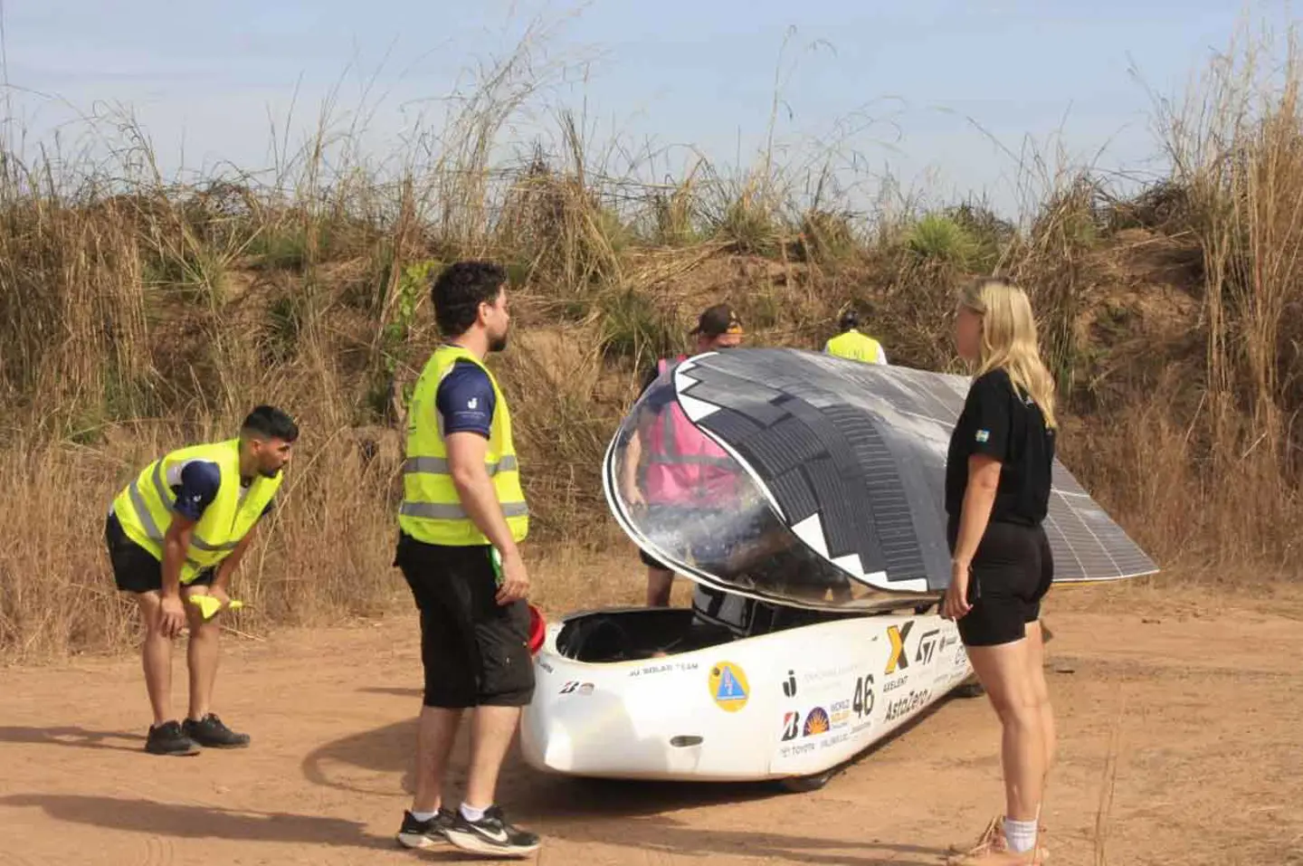 Members from JU Solar Team '25 standing talking around the solar car Nova Lumia