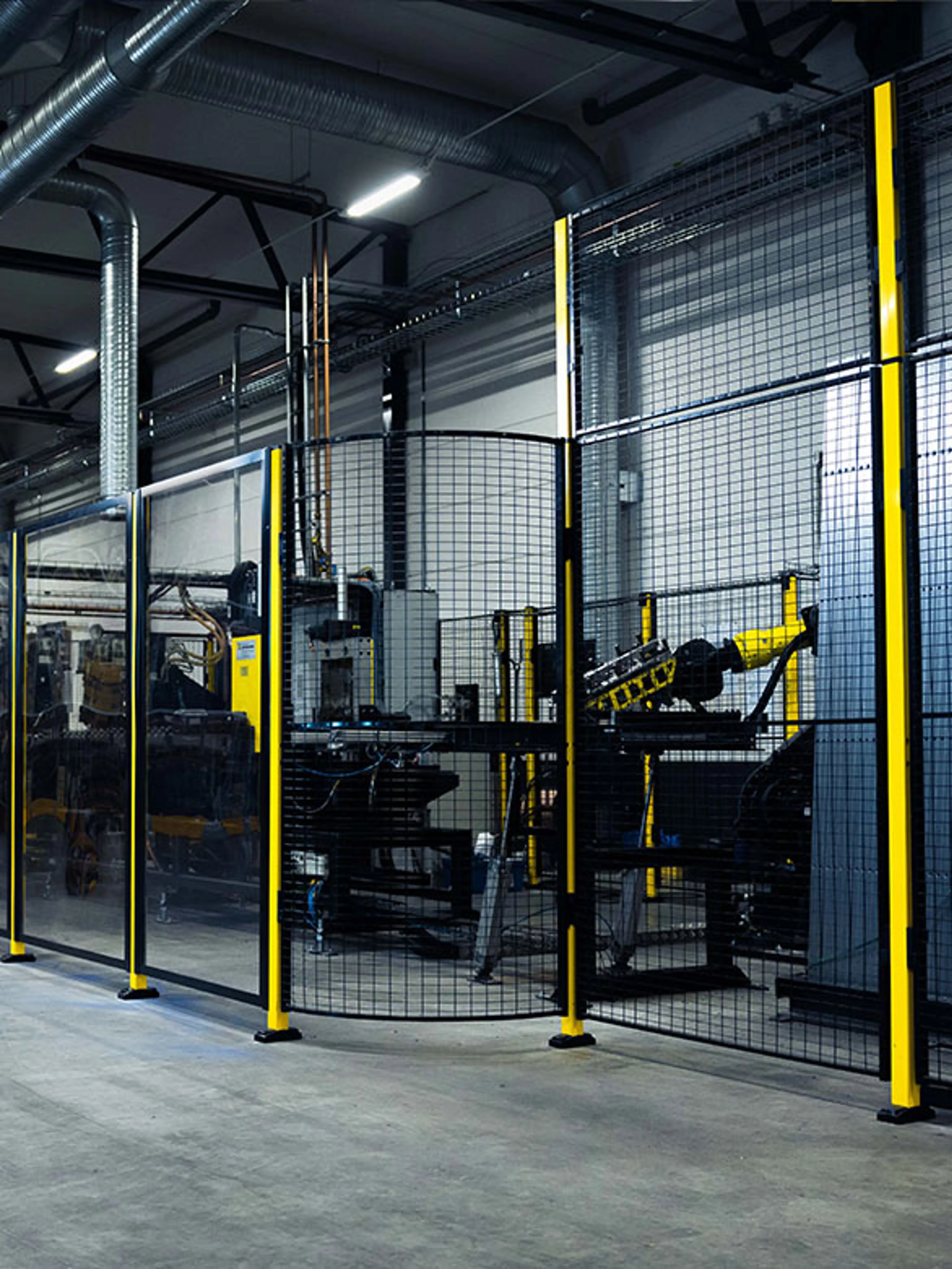 Industrial machine guarding system with yellow and black protective fencing, ensuring worker safety and regulatory compliance in a manufacturing environment. The barrier prevents unauthorized access to hazardous machinery, reinforcing workplace safety standards.