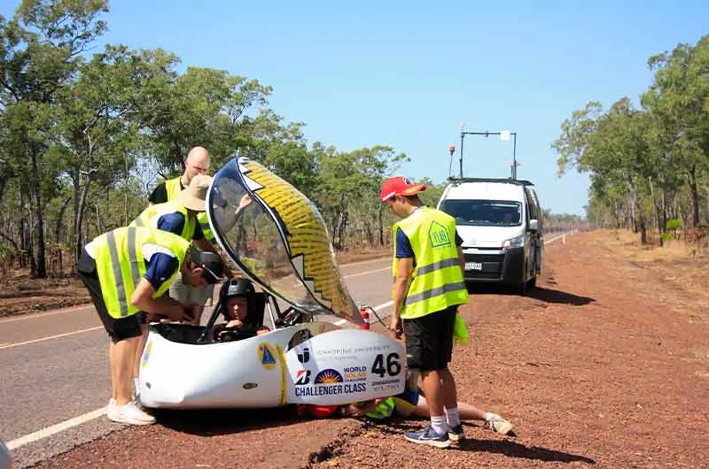 Three members of JU Solar Team 2025 working on the solar car Nova Lumia on the side of a road in Australia