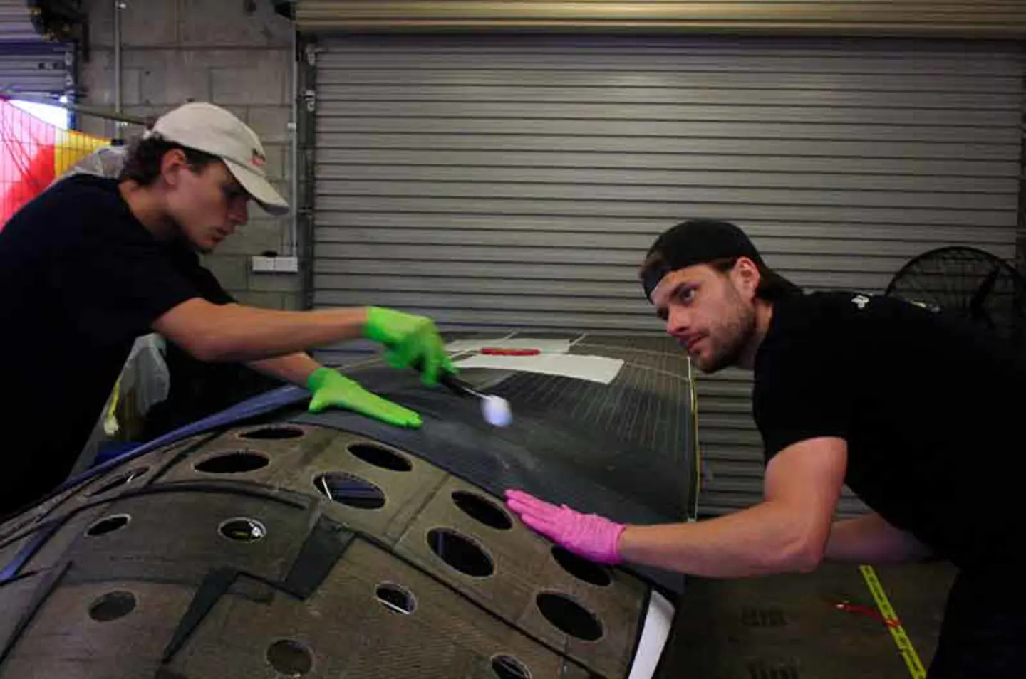 Two male members of the JU Solar Team working on preparing the roof of the solar car Nova Lumia for the solar panels