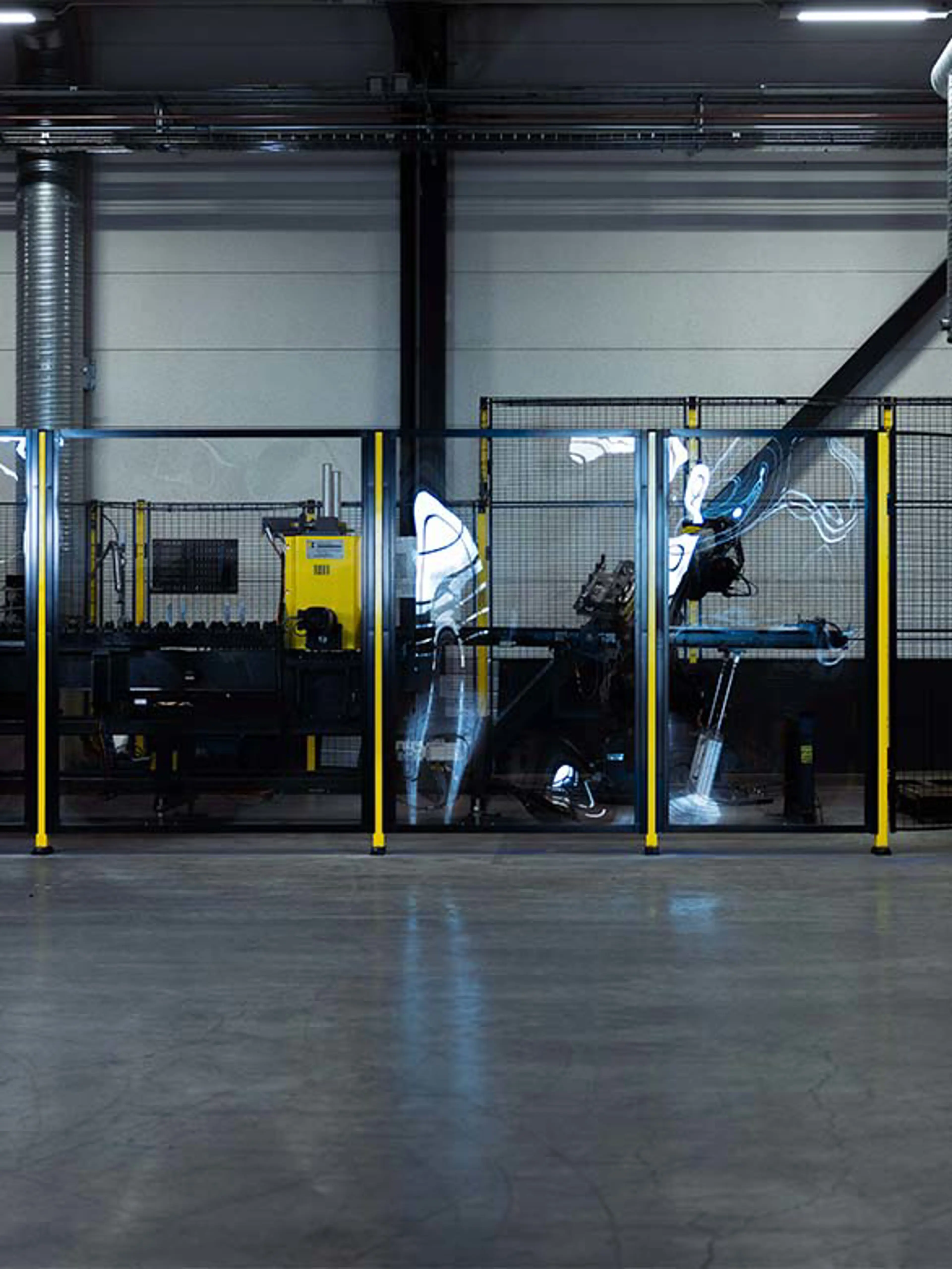 A robotic workstation enclosed by transparent safety fencing, ensuring secure machine operation while maintaining visibility. The image highlights the role of monitoring systems as an alternative to movable guards, enhancing industrial safety and efficiency.