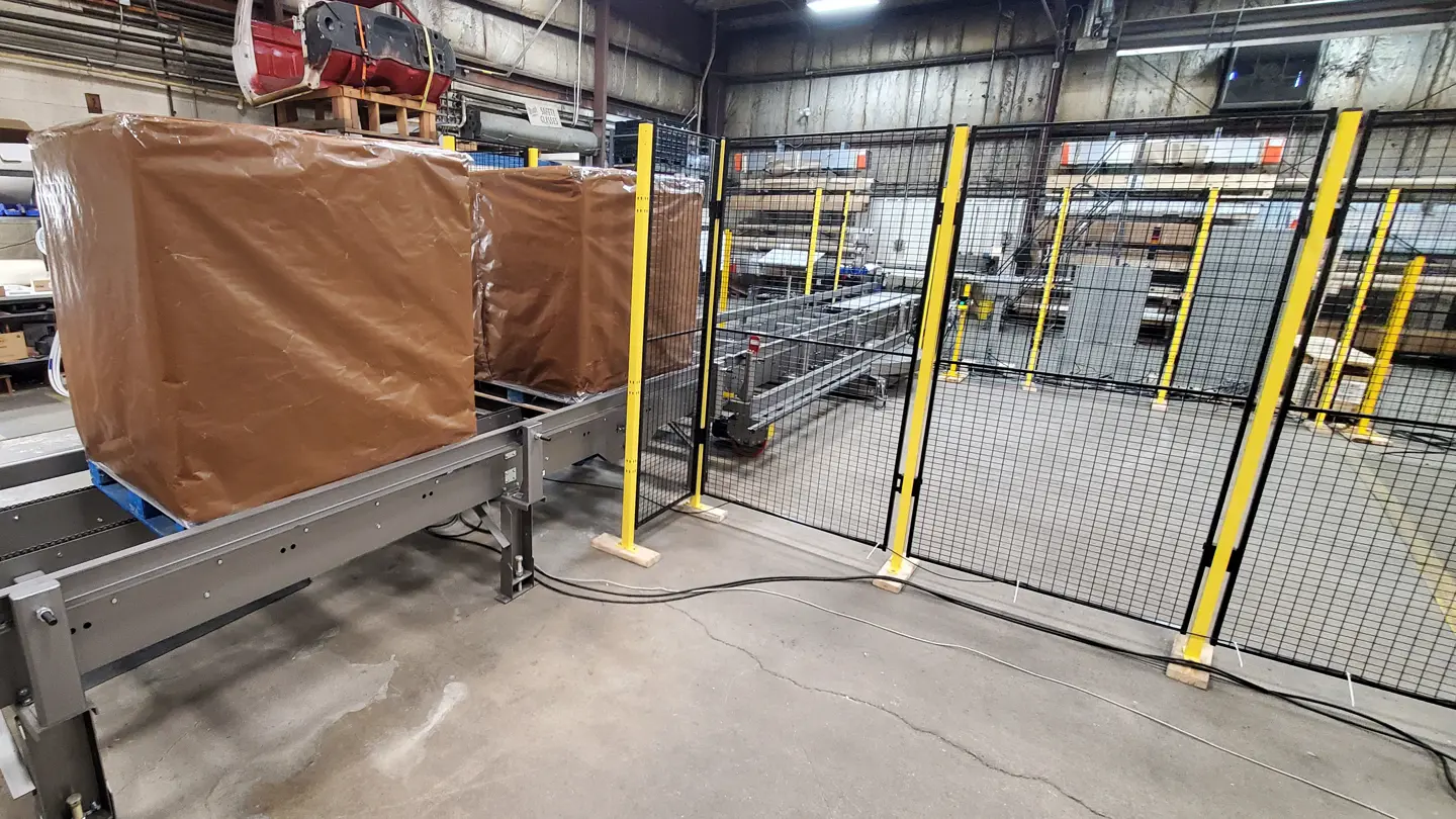 Two big boxes on a palletizing system in a warehouse with safety fences around