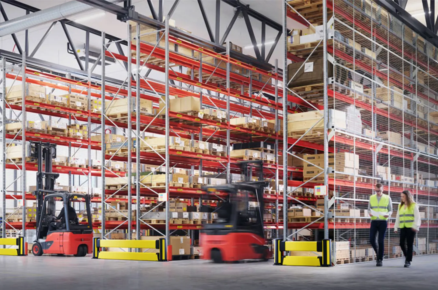 Warehouse aisle with pallet racking protected by polymer impact barriers and forklift traffic