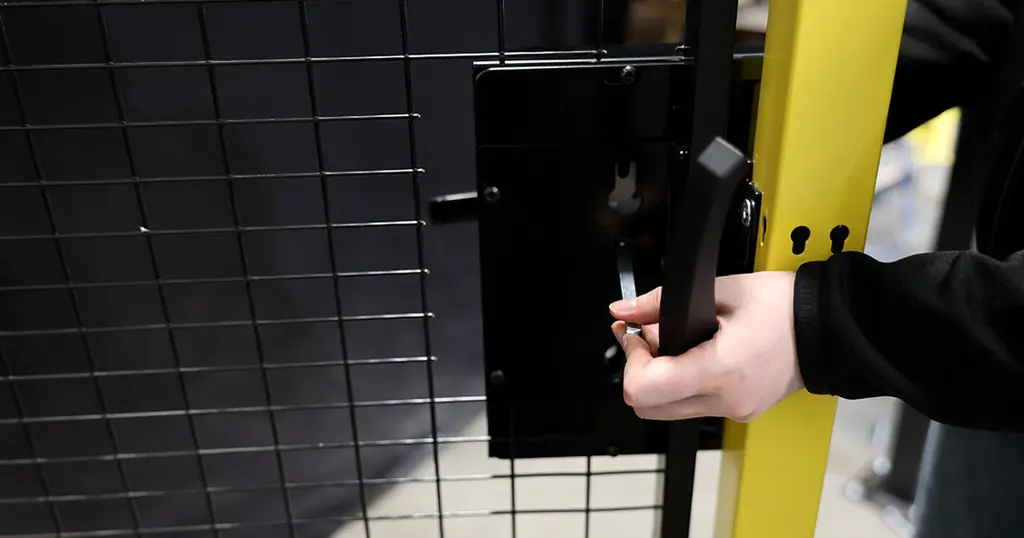 Hand holding a cylinder handle lock mounted on a black mesh panel 